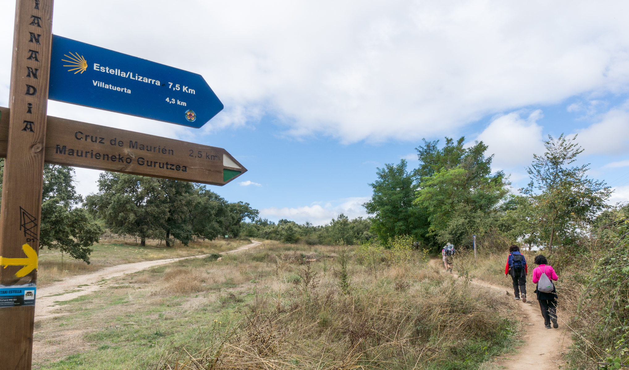 Pilgrims on the Camino Francés pass a sign stating that 7.5 km remain before reaching Estella, Spain | Photo by Mike Hudak