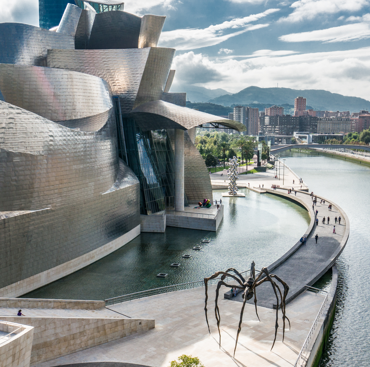 View from a bridge of the Guggenheim Museum Bilbao that includes its exterior sculptures Tulips by Jeff Koons and Maman by Louise Bourgeois | Photo by Mike Hudak