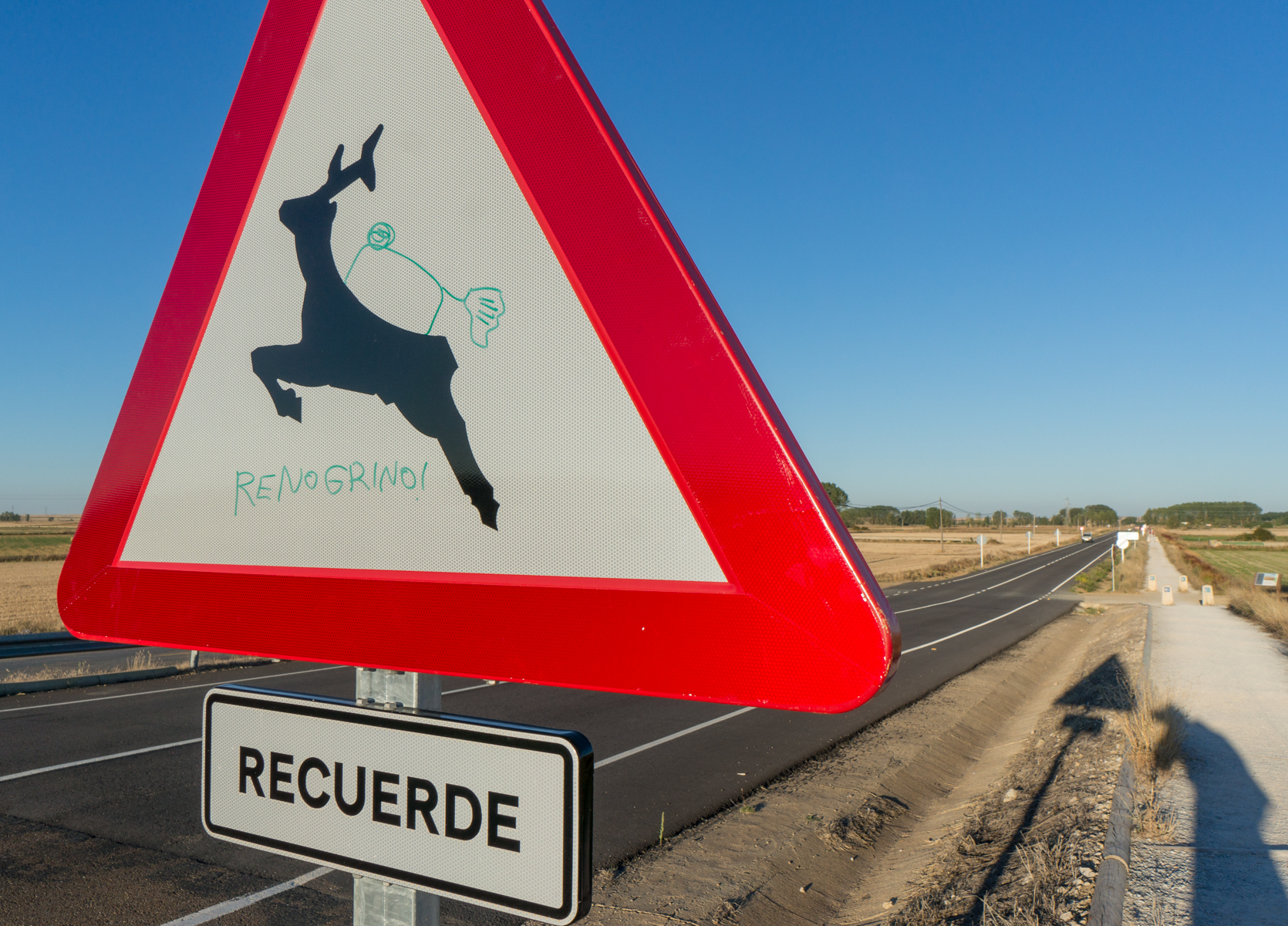 Graffiti-enhanced traffic sign on a highway parallel to the Camino Francés west of Frómista, Spain | Photo by Mike Hudak