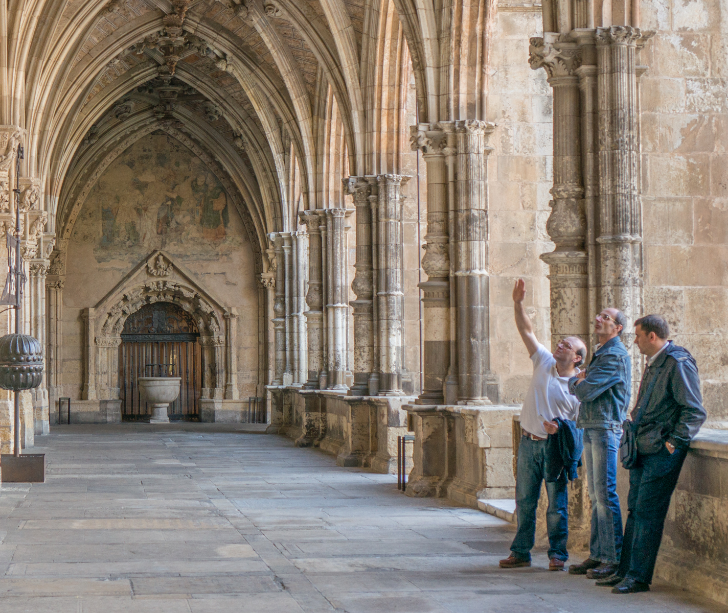 Three men discuss a faded fresco depicting the crucifixion of Jesus at the 13th century cloister adjoining the Catedral de Santa Maria de Regla de Leon (Spain) | Photo by Mike Hudak