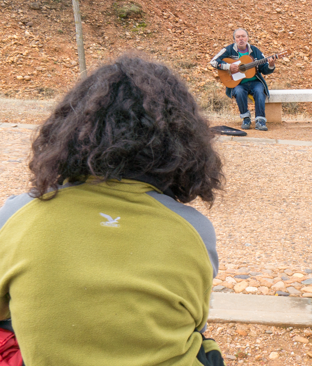 A Camino pilgrim listens to a local guitarist before continuing on to San Justo de la Vega, Spain | Photo by Mike Hudak