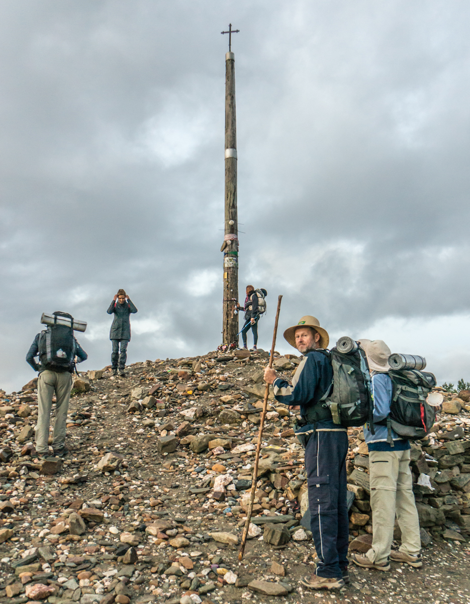 Before sunrise, Camino pilgrims stand before La Cruz de Ferro (The Iron Cross) | Photo by Mike Hudak