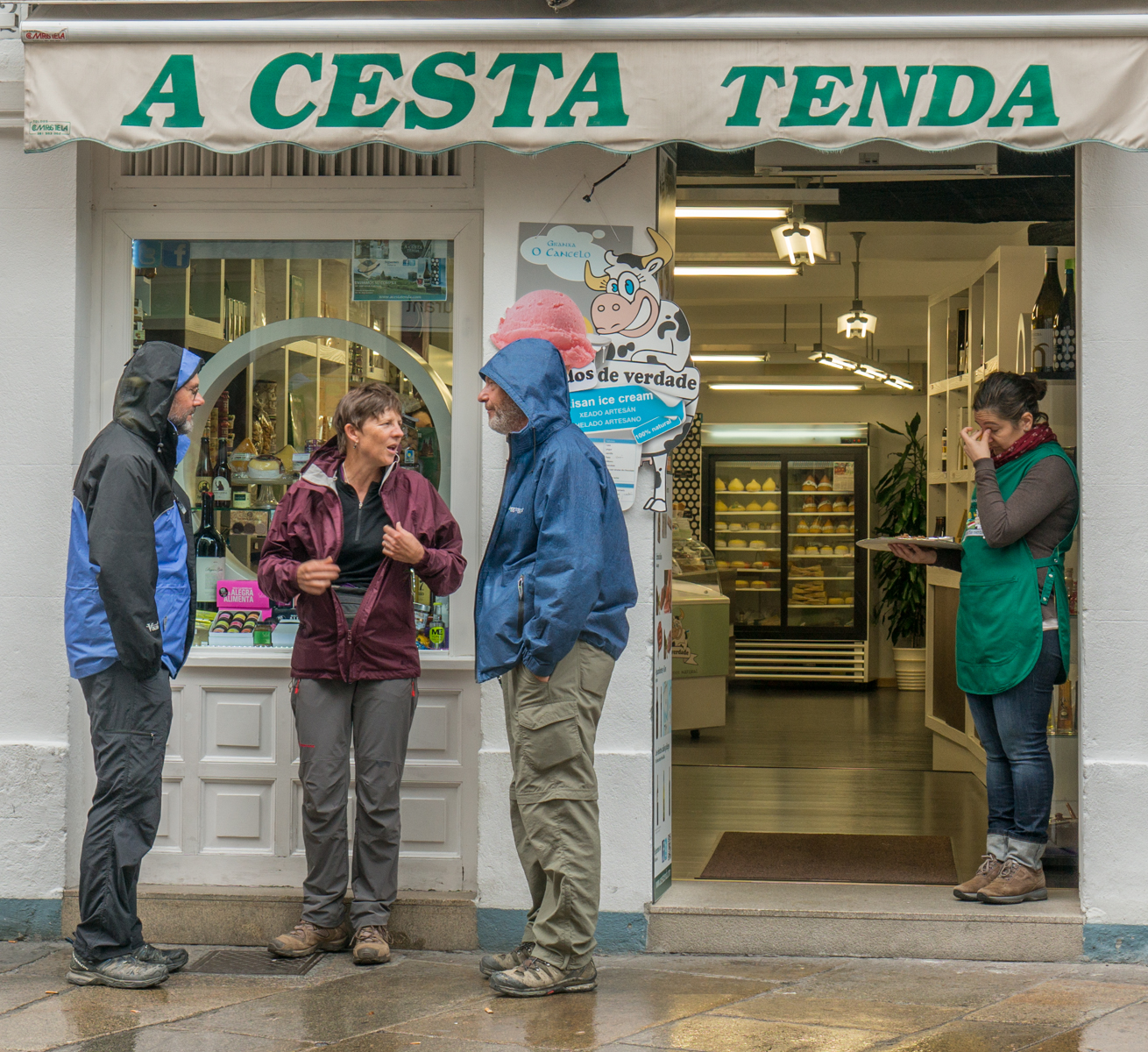 Camino pilgrims stand in front of A Cesta Tenda during rain in Santiago de Compostela | Photo by Mike Hudak.