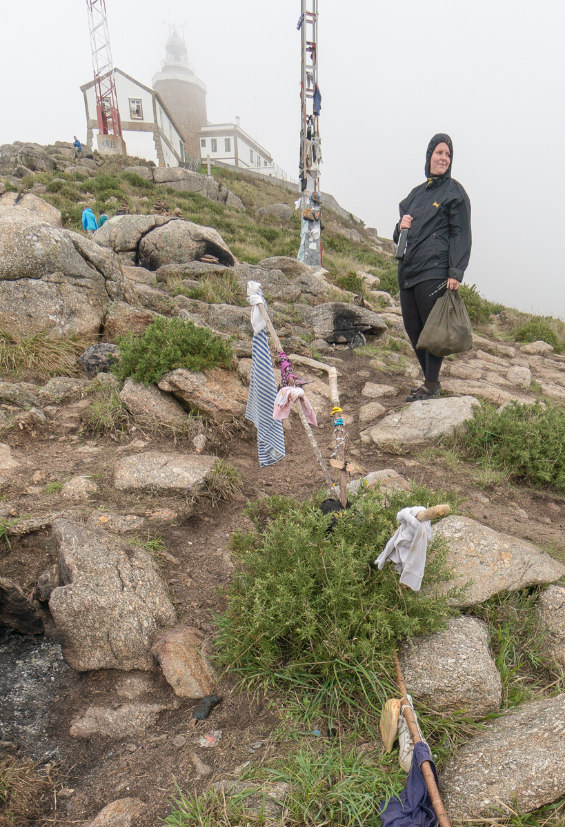 Finisterre Lighthouse and makeshift memorial viewed from a slope steeply descending toward the Atlantic Ocean | Photo by Mike Hudak